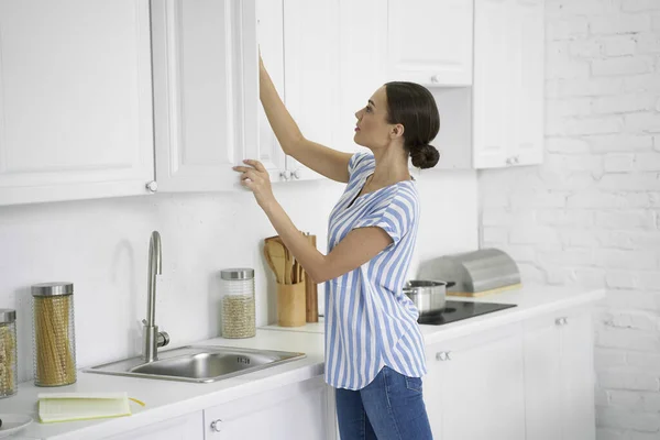Vrouw het openen van de keuken kast stock foto — Stockfoto