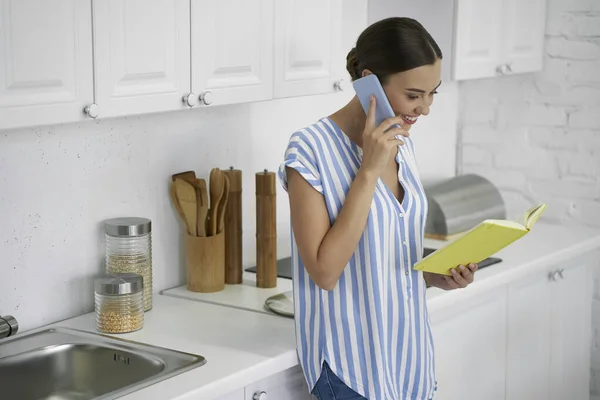 Позитивна жінка розмовляє по телефону на кухні фото — стокове фото