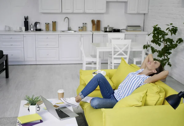 Kanepede dinleniyor ve gülümsüyor.