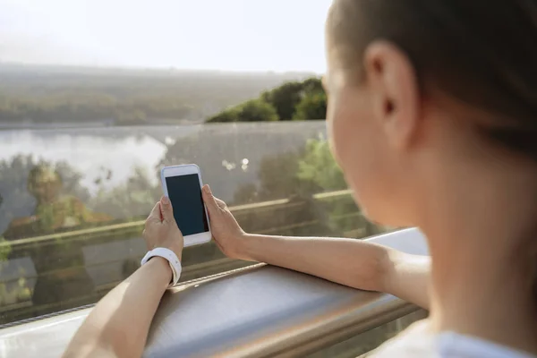 Young lady with mobile phone on bridge