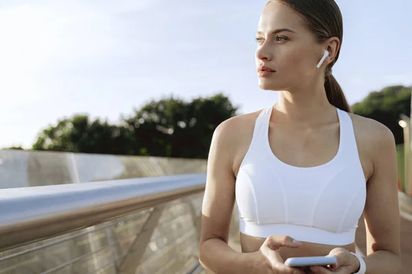 Jeune dame sportive dans les écouteurs avec mobile — Photo