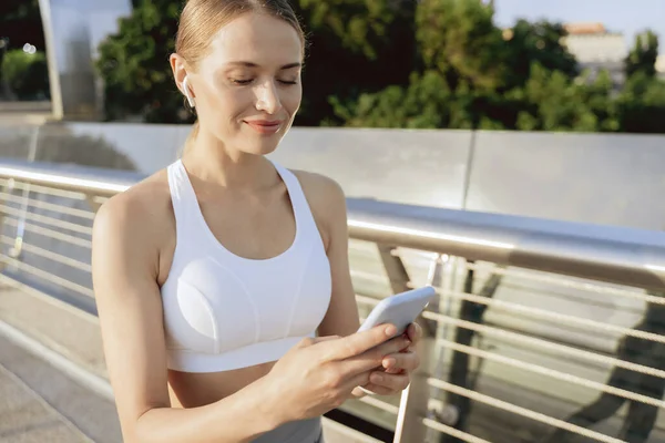 Happy dame athlétique dans les écouteurs avec téléphone — Photo