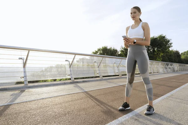 Nyugodt sportos hölgy mobiltelefonnal edzés közben — Stock Fotó