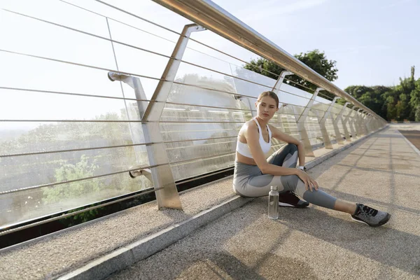 Rustige dame in sport dragen zittend op brug weg — Stockfoto