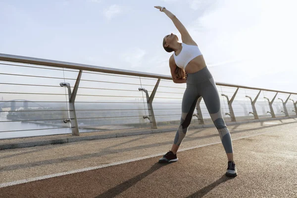 Sportiv dam gör sida kropp böja med handen upp — Stockfoto