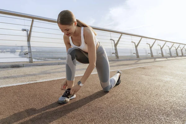 Sportivo giovane signora cravatta lacci prima di correre — Foto Stock