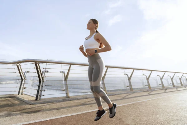 Sportos hölgy fut a helyén gyalog hídon — Stock Fotó