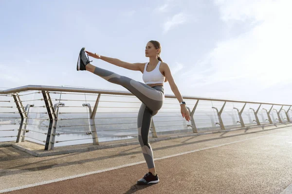 Sportif bayan yaya köprüsünde bacak sallıyor.