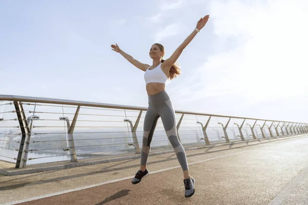 Yürüyüş köprüsünde zıplayan neşeli bayan.