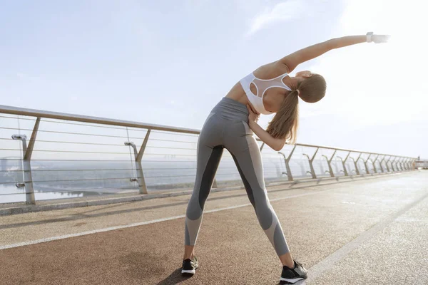 Genç atletik bayan yan vücut büküyor.