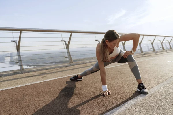 İnce atletik bayan yan bacakları esnetiyor.