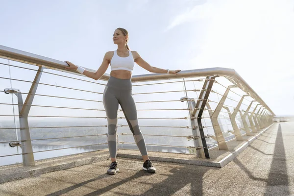 Giovane signora atletica in abbigliamento sportivo sul ponte a piedi — Foto Stock