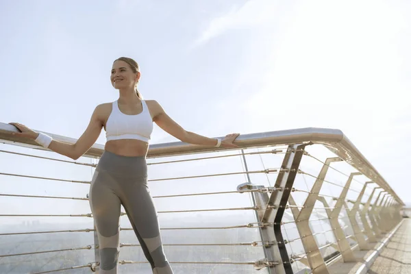 Felice signora atletica in abbigliamento sportivo sul ponte a piedi — Foto Stock