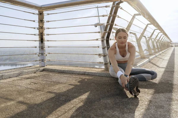 Sportif bayan köprüde esneme antrenmanı yapıyor.