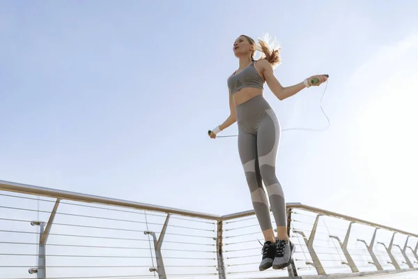 Joven mujer deportiva saltar la cuerda en el puente —  Fotos de Stock