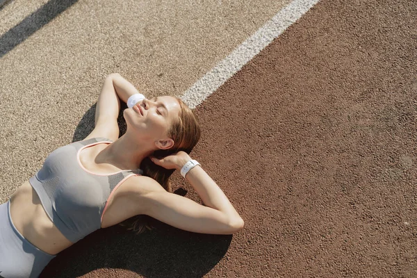 Sportos hölgy élvezi napsütés feküdt a földön — Stock Fotó