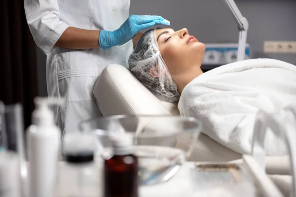 Kosmetikerin in sterilen Handschuhen Putzfrau Gesicht mit weichem Polster — Stockfoto