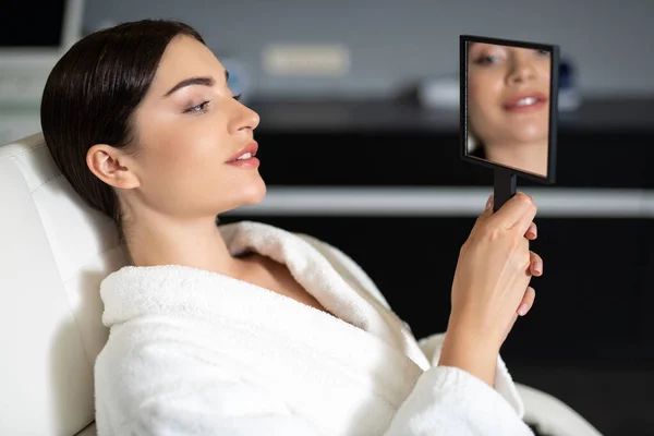 Krásná mladá žena se dívá do zrcadla — Stock fotografie