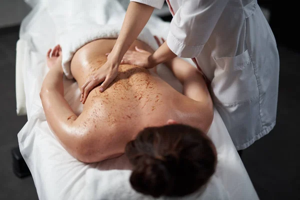 Masérka dělá terapeutickou masáž zad pro mladou ženu — Stock fotografie