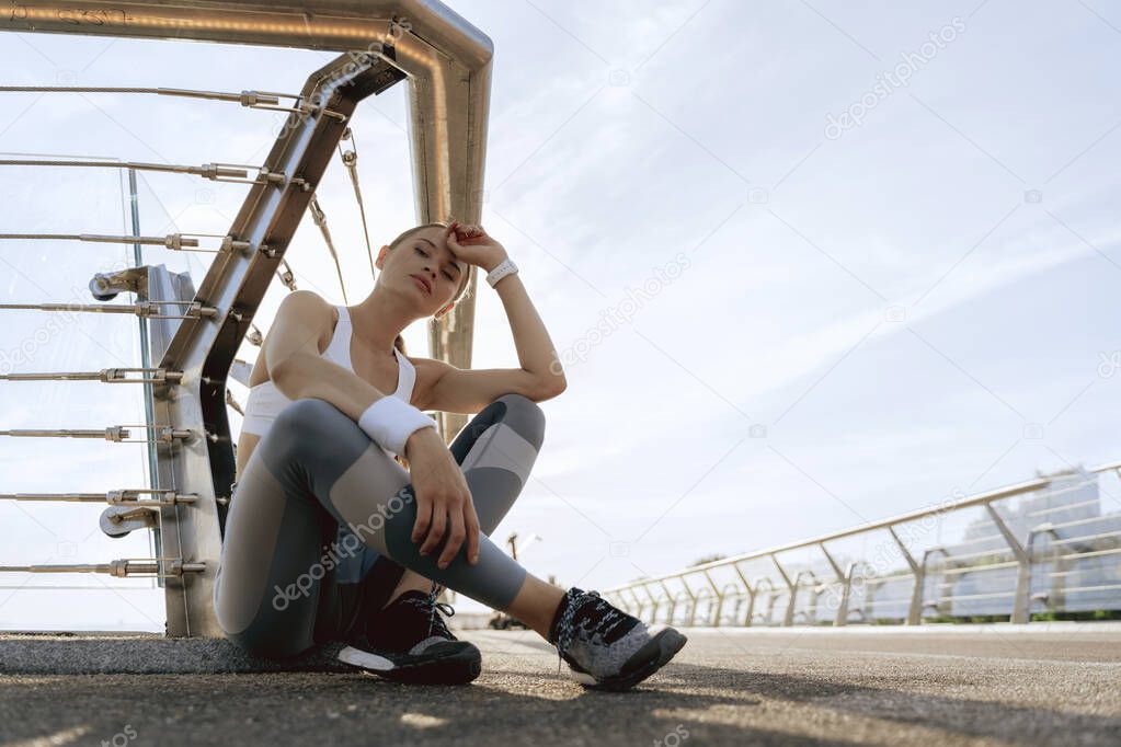 Sportive lady sitting on foot bridge ground