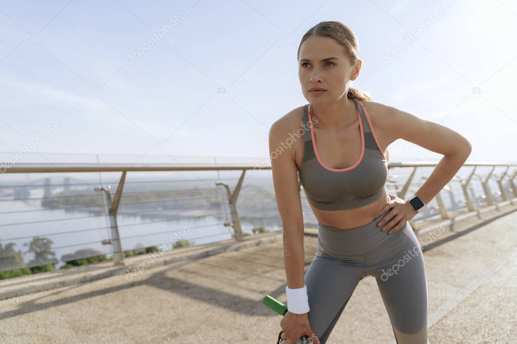 Sportive lady with jump rope on foot bridge