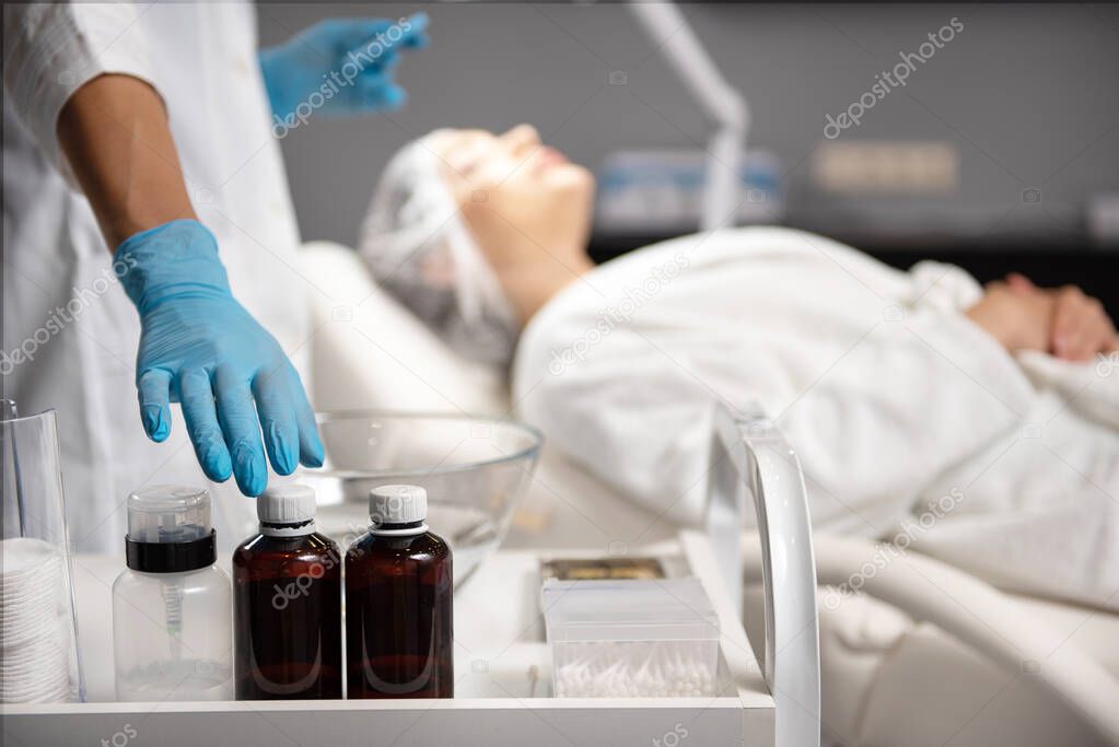 Beautician in sterile gloves reaching for mineral cleansing liquid