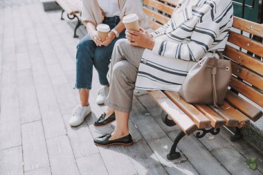 İki beyaz kadın bankta oturuyor.