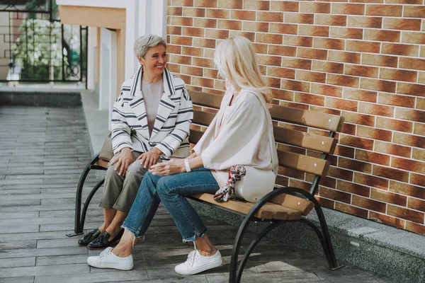 Alegre señora mayor sentada al lado de un amigo — Foto de Stock