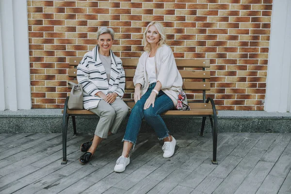 Mujeres alegres sentadas en el banco al aire libre —  Fotos de Stock