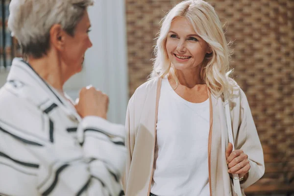 Nöjd medelålders kvinna tittar på sin äldre vän Stockbild