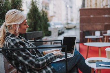 Bir kafede bir dizüstü bilgisayar üzerinde çalışan kadın