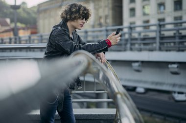 Akıllı telefon kullanan genç bir motorcu.