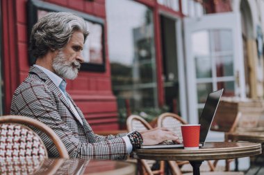 Kafe masasında dizüstü bilgisayar kullanan sakin bir adam.