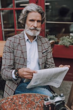 Kendine güvenen zarif bir adam, en son haber bülteni fotoğrafını okuyor.