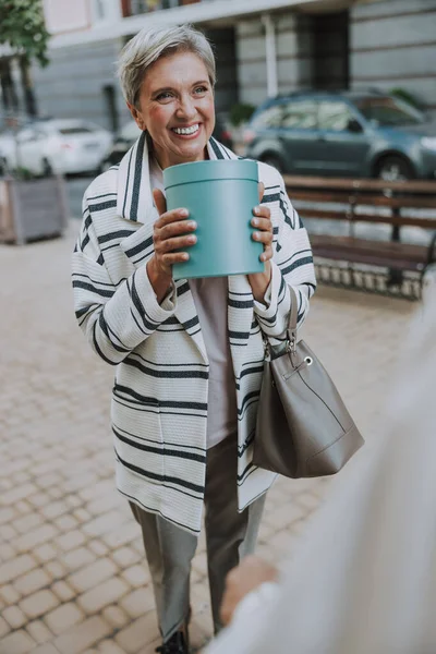 Piacevole attraente donna anziana in possesso di un regalo — Foto Stock