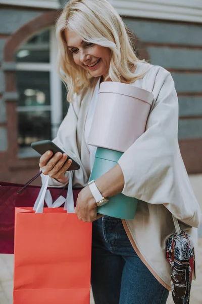 Atrakcyjna kobieta z zakupami przy użyciu smartfona — Zdjęcie stockowe