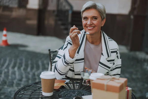 Улыбающаяся женщина ест десерт в кафе — стоковое фото