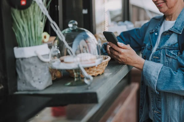 Akıllı telefonlu bir kadın büfenin yanında duruyor. — Stok fotoğraf