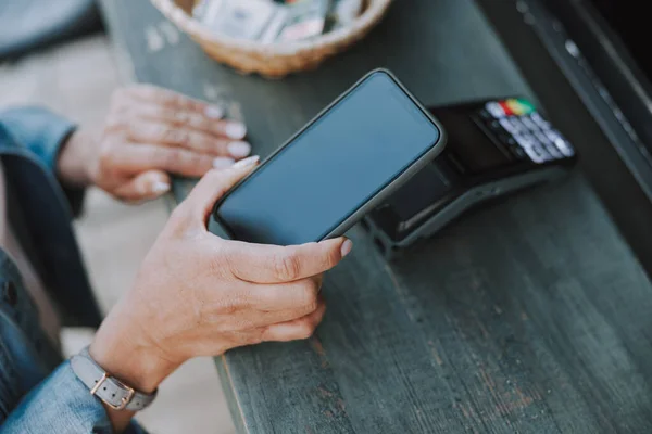 Vit kvinna hand betalar via en smartphone — Stockfoto