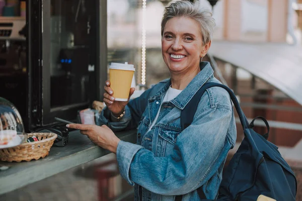 Улыбающаяся красивая пожилая леди заказывает кофе на открытом воздухе — стоковое фото