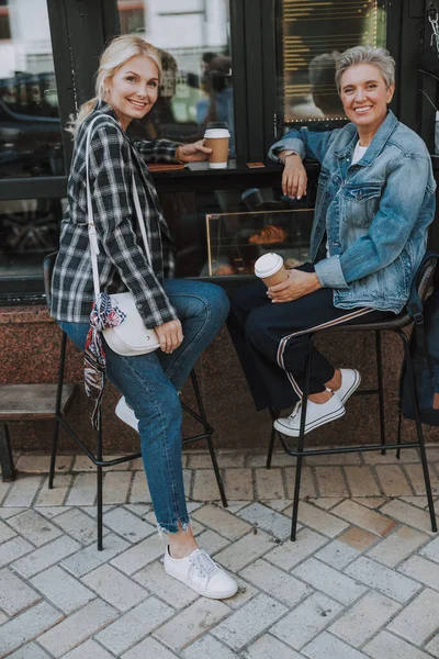 Elinde kahve bardakları olan kadınlar dışarıda oturuyor. — Stok fotoğraf