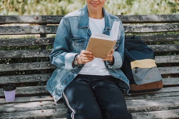 Sonriente mujer caucásica leyendo un libro al aire libre — Foto de Stock