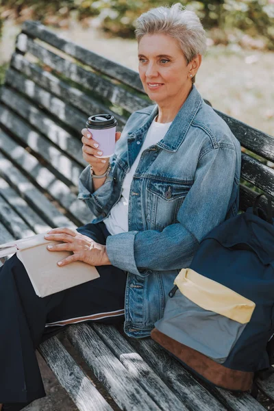 Señora con un libro y café sentado afuera — Foto de Stock