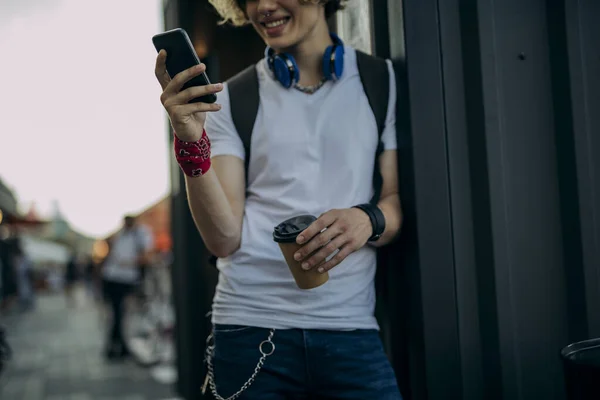 Chico alegre con teléfono inteligente beber café al aire libre stock foto — Foto de Stock