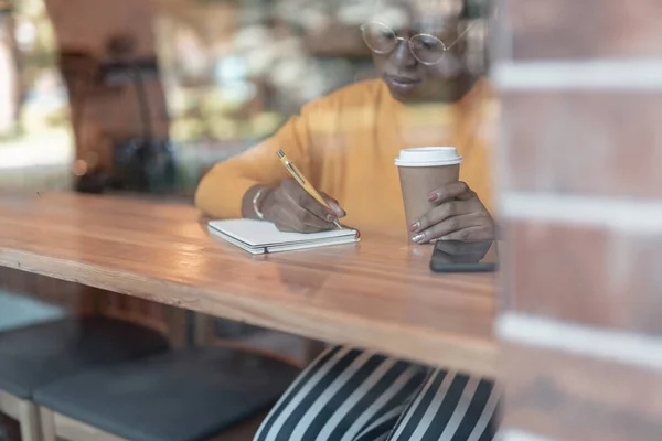 Vrouw maakt notities in cafetaria stock foto — Stockfoto