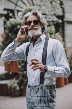 Puro ve akıllı telefondan fotoğraf çeken neşeli sakallı adam.