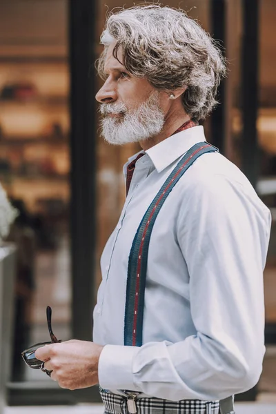 Стильный мужчина стоит на улице в рубашке с подтяжками фото — стоковое фото