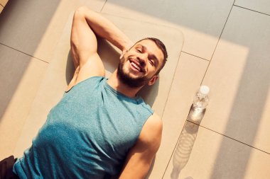 Neşeli genç adam evde yerde yatıyor.