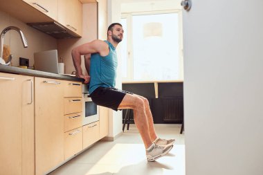 Atletik genç adam mutfakta çalışıyor.