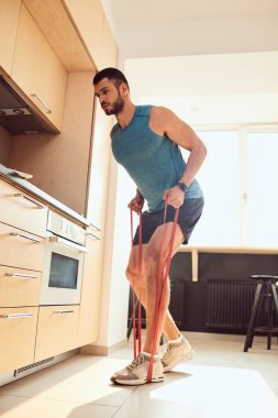 Lastik jimnastik bandıyla egzersiz yapan yakışıklı bir beyefendi.